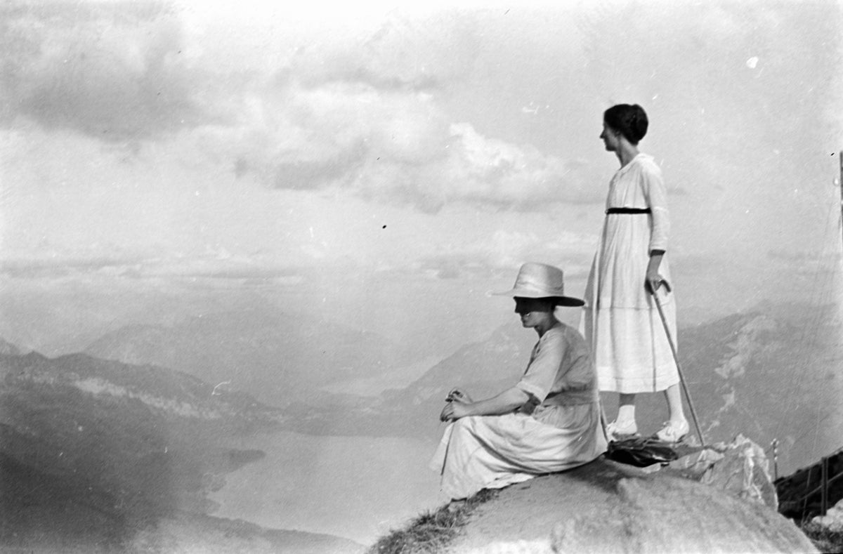 man and woman standing on rock in grayscale photography
