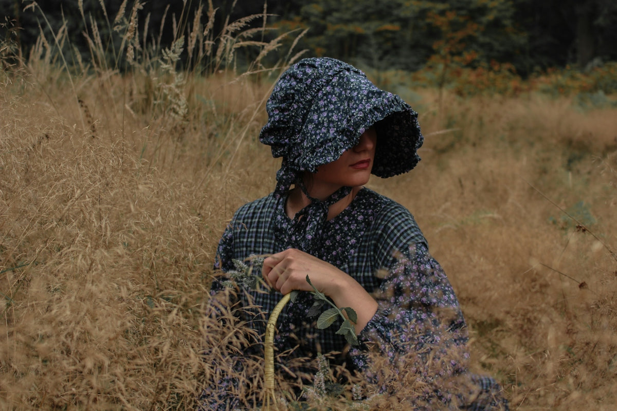 Woman in bonnet sitting in tall dry grass