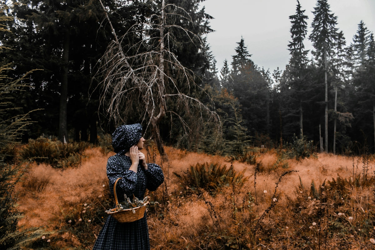 Woman in vintage dress with basket in forest